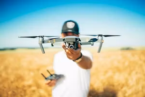 Pilot holding a drone over a wheat field